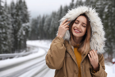 年轻女子穿着温暖的衣服在户外空间发短信。 寒假