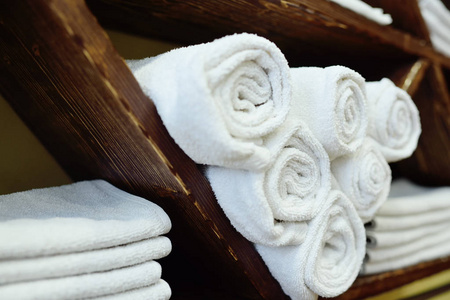 白色干净的毛巾整齐地折叠在美容院或理发店的木架子上