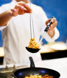 厨师烹饪意大利面厨师在厨房的盘子里供应意大利面。