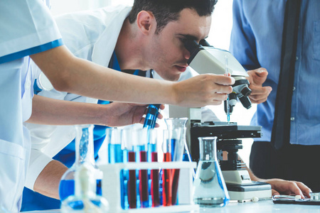 一组科学家穿着实验室外套在实验室工作，同时检查试管和科学仪器中的生物化学样品。科学技术研发学习理念..