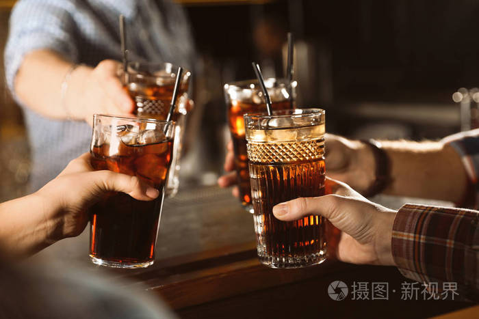 一群朋友在室内餐桌上用可乐碰杯,特写镜头