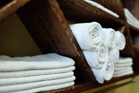 白色干净的毛巾整齐地折叠在美容院或理发店的木架子上