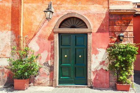 房子旧红墙上的绿色门。 意大利罗马。