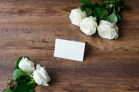木制背景上有白色玫瑰的贺卡。 复古调色图像
