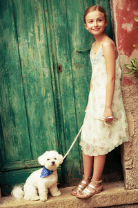 一个可爱的女孩的肖像，白色马耳他狗在一个旧的门背景。