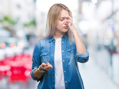 年轻的金发女人在孤立的背景上闻到一些臭味和令人恶心的难以忍受的气味，用手指在鼻子上屏住呼吸。 难闻的概念。