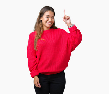 年轻漂亮的黑发女人穿着红色的冬季毛衣，在孤立的背景上指点着成功的想法。 退出并快乐。 一号。