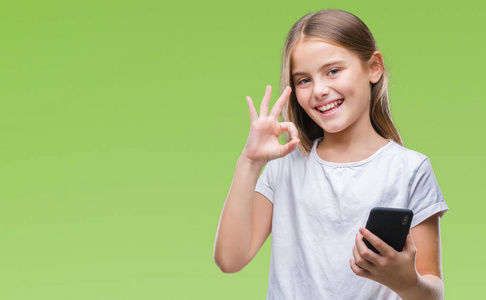 年轻美丽的女孩发送信息，用smarpthone在孤立的背景上发短信，用手指做OK标志，很好的符号