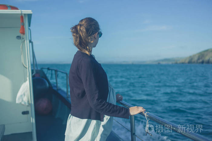 夏天,一个年轻的女人站在船上的栏杆旁