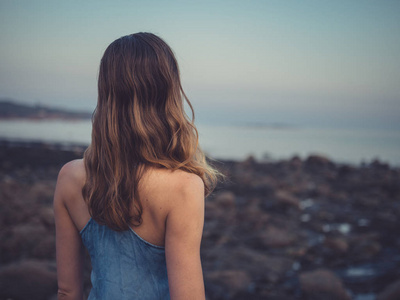 日落时分，年轻女子站在海岸上