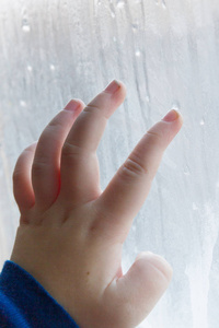 s hand draws patterns on the frozen window in winter