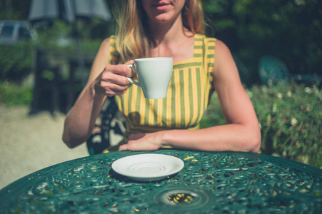 夏天，一个年轻的女人正在花园外面喝咖啡