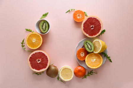 热带水果框架从橙色柠檬橘子和猕猴桃粉红色纸背景。 健康的食物概念。 平躺着。 顶部视图