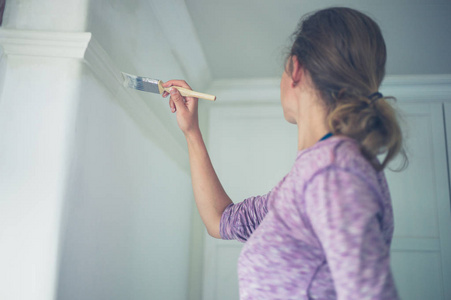 一位年轻女子正在粉刷天花板