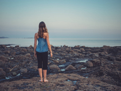 日落时分，年轻女子站在海岸上