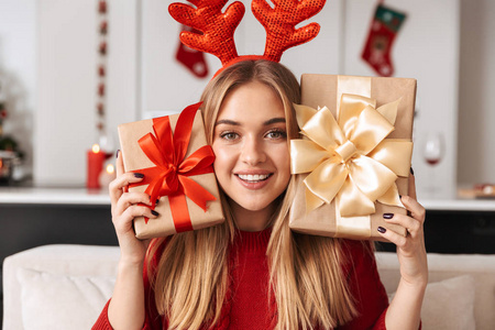 20岁的漂亮女孩在庆祝圣诞节时坐在客厅的沙发上，放着礼品盒