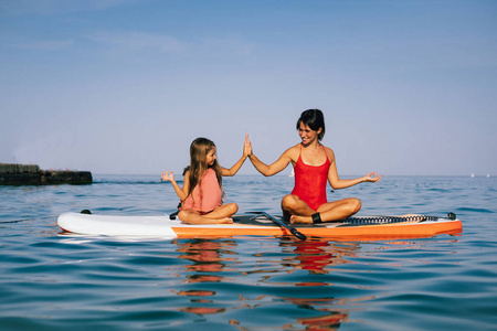 妈妈和小女儿在划桨板上做瑜伽