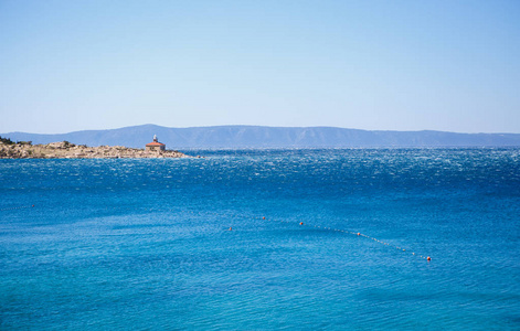 克罗地亚美丽的亚得里亚海海岸。岩石海岸，悬崖上有灯塔。清澈的海湾，用于在异国情调的克罗地亚度假胜地潜水和游泳。