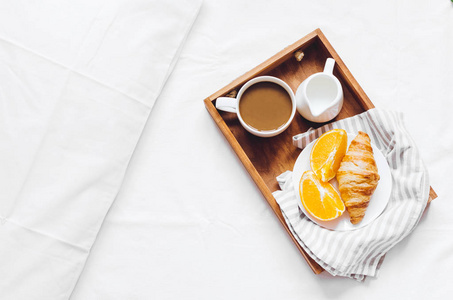 浪漫情人节早餐在床上，托盘与新鲜牛角面包，一杯咖啡浓缩牛奶和新鲜橙子。早上好享受慢生活。上景。复制空间。