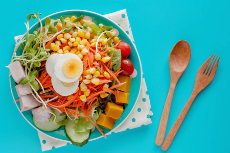 新鲜沙拉蔬菜，有煮鸡蛋木勺和叉子，蓝色背景，健康饮食，饮食概念