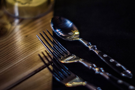 餐馆里桌子上有两把叉子和一把勺子。 服务前的表设置。 深色房间