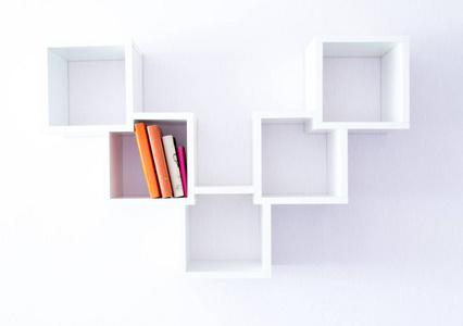 白色墙壁上的一个现代白色书架，上面有一双书。 极简主义风格。