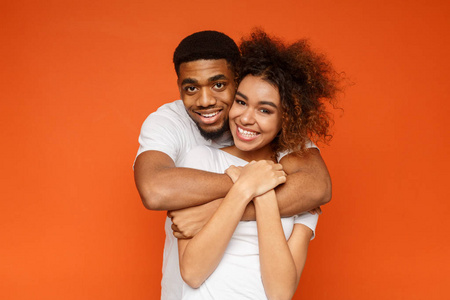 年轻可爱的非洲裔美国夫妇摆在橙色的背景