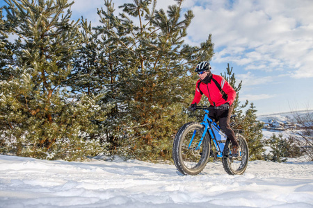一个人骑着一辆山地车，在雪地上戴着大肥轮胎和头盔。胖自行车。