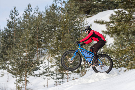 一个人骑着一辆山地自行车，在雪地上戴着厚厚的轮胎和头盔。 胖自行车。