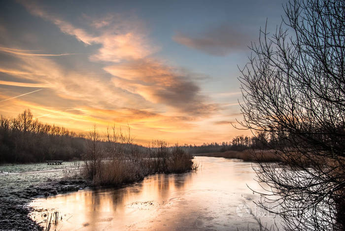 冰冻的河流和芦苇在寒冷的冬季早晨和戏剧性的早晨天空在迪姆伯斯迪门