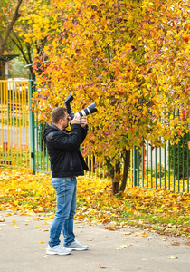 男人拍摄秋天的叶子。 专业摄影师金秋