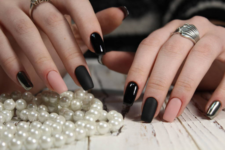 美丽的黑色指甲和美丽的背景上的珍珠