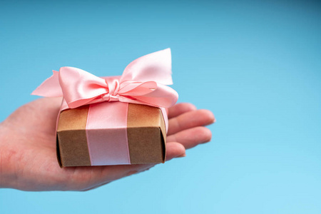 s hands holding gift box Packed in Kraft paper with pink ribbon 