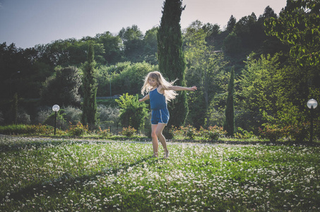 女孩在充满鲜花的绿色草地上嬉戏