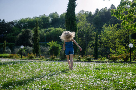 女孩在充满鲜花的绿色草地上嬉戏