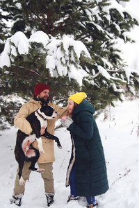 幸福的夫妇在爱有乐趣在雪地里与他的小狗