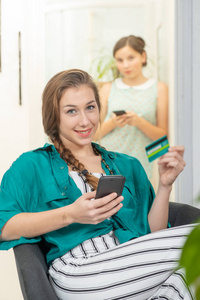 带着智能手机在网上购物的微笑的年轻女子