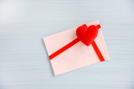 礼品卡饰有红色丝带蝴蝶结白色木质背景上的心信封爱情邮件情人节贺卡或代金券