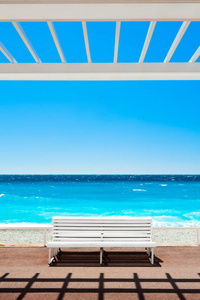 在尼斯法国安格拉伊斯长廊上的白色长凳。 美丽的绿松石海和海滩