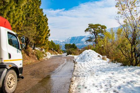 乌菲尔道冬季在班尼赫特达尔豪西希马恰尔邦印度与侧满雪。在蓝天背景和云彩的道路旁，从柏油路上看到美丽的冬季景色