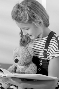 小女孩正在给泰迪熊读书