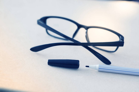 蓝调白纸上的钢笔和眼镜，用来描述今天生活的人们的日常活动
