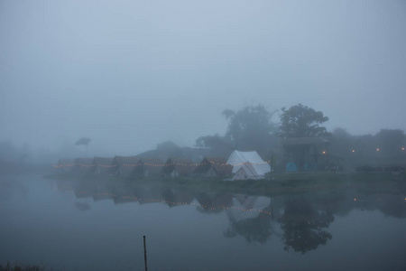 在雾蒙蒙的早晨，用山景把帐篷铺在河边。