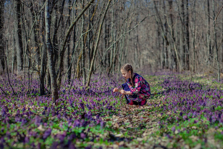 一个美丽的小女孩和延胡索花的肖像。 在阳光明媚的日子里在春天的森林里散步。