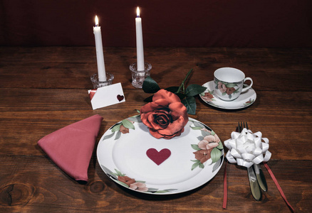 花型精美瓷器餐具，配配盘子杯和碟子。 粉色玫瑰粉色餐巾银器白色蜡烛和卡片