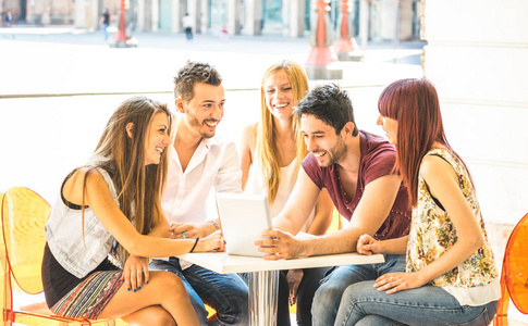 朋友小组坐在餐厅酒吧玩平板电脑连接社区青年学生使用便携式电脑千禧一代概念分享内容在社交媒体上