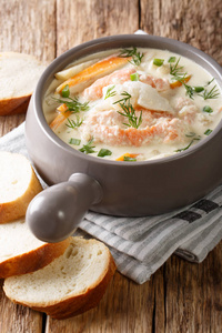 美味的奶油鱼汤与鳕鱼和鲑鱼接近在一个碗与新鲜面包在桌子上。 青筋