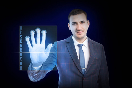微笑的男人，穿着西装，打着领带，用手指触摸透明的屏幕，以识别蓝色背景的未来概念