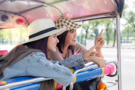 美丽的旅游妇女指着旅游场所。 迷人的美丽的旅行者女性在暑假期间享受旅行。 他们坐着汽车人力车环游城市