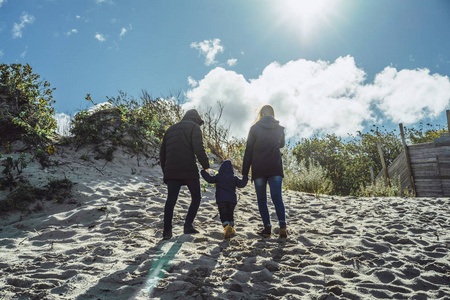 一个带着孩子的年轻家庭周末和一个小孩子一起度过寒冷的波罗的海沙滩温暖的夹克家庭周末